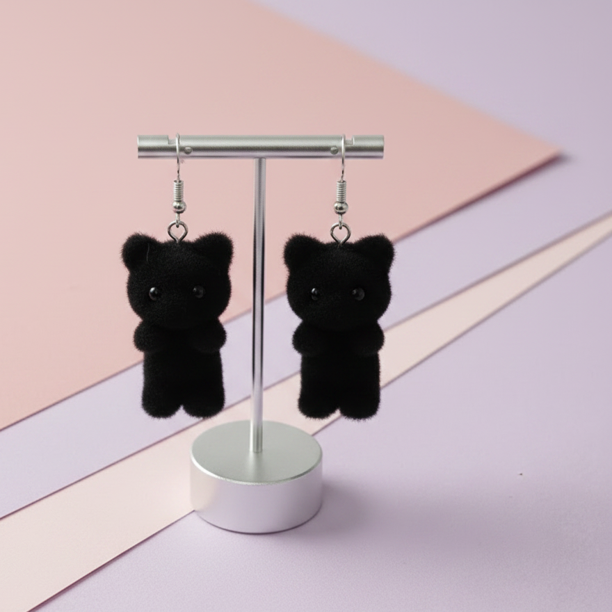 Black cat-shaped earrings on a stand with a pastel background