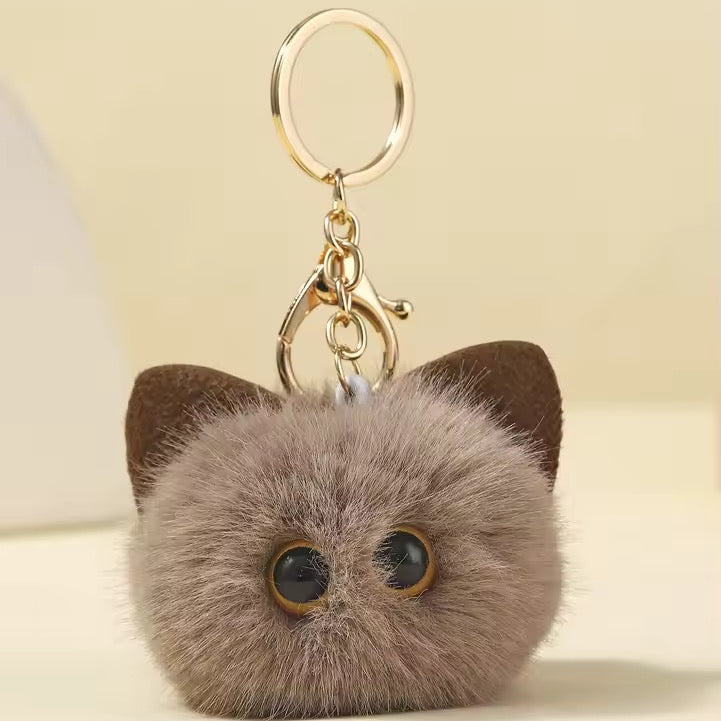 Cat-shaped keychain with fluffy texture on a light background