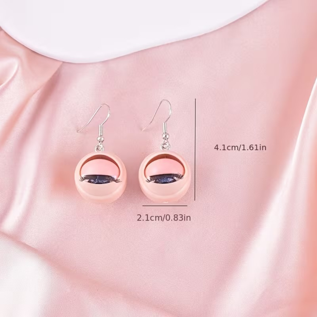 Pair of pink earrings with measurements on a pink fabric background